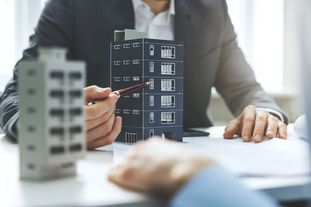 real estate developer pointing at building model